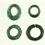 Four circular green glass beads