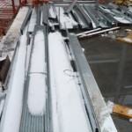 Snow and ice cover the construction materials.