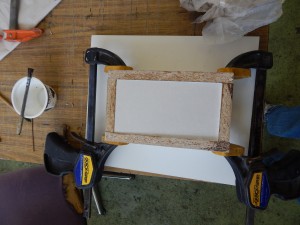 The top half of the mold box is filled with the plaster/silica mix. Then, the mold box is flipped. The clay is removed, and the other half of the mold box is filled with the plaster/silica mix.