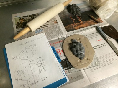 A diagram of the desired exterior shape, along with the set up before wax is applied to the silicone grape cluster.