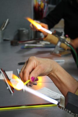 Using a mixture of natural gas and oxygen, the 4,000 degree flame melts the glass stick into a ball.