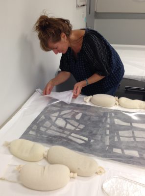 Luisa Casella from West Lake Conservators checks a photograph that has been humidifying to see if it is ready to be transferred to the flattening table.