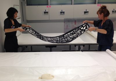 Laura and Luisa move a humidified and relaxed photograph to a prepared table for flattening and drying.