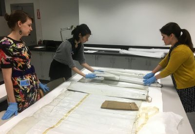 Bonnie, Laura, and Moya Dumville from West Lake Conservators carefully unroll objects to assess their condition before proceeding with treatment.