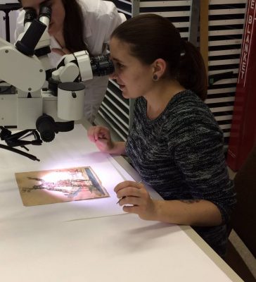 Photograph of Colette looking through a microscope at a print