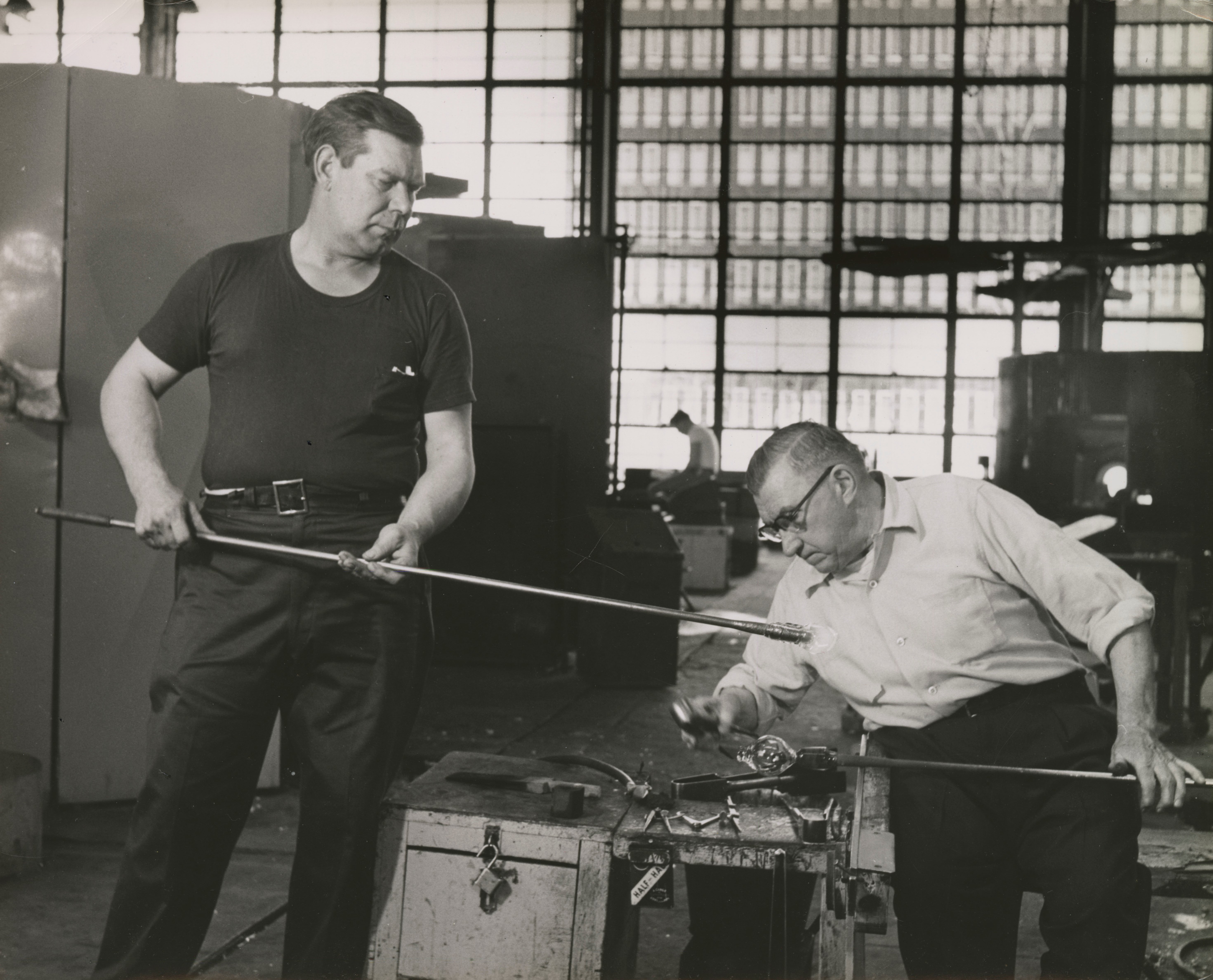 Photograph of a gatherer and gaffer working together on a piece of glass