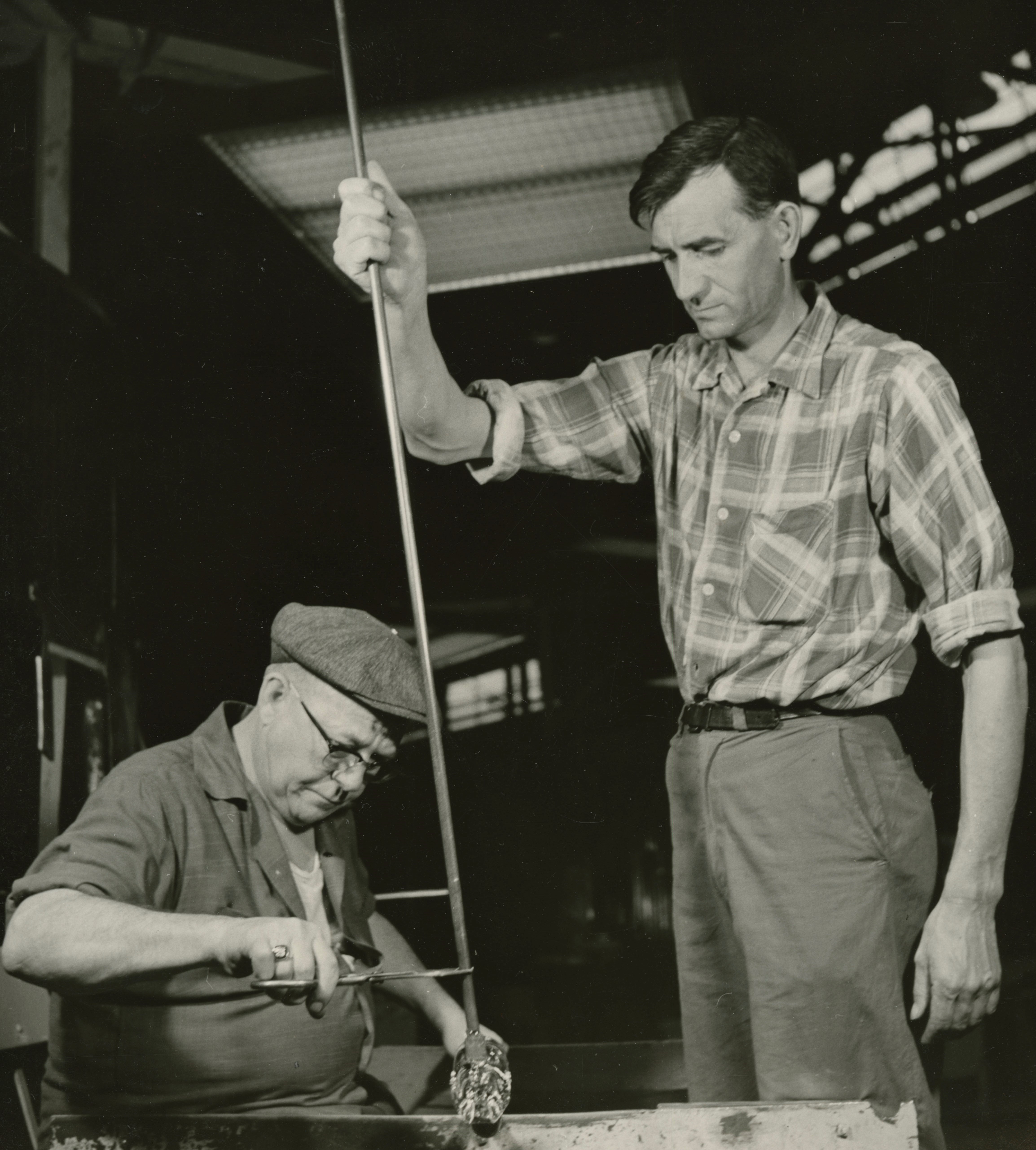 Photograph of a gatherer and gaffer working together on a piece of glass