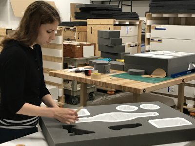 Noelle Ward, Collections Intern, pads each cutout with a soft material for protection.