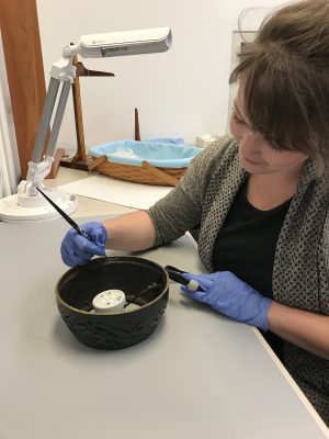 Christy Cook, Associate Registrar, labels the lamp’s metal base with its number.