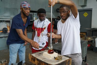 Jalen Pittman assists N'Kosi Barber (mentor) with a glass heart as Julian watches.