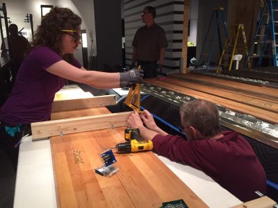 Preparators Lindsay and Steve brace ceiling panels with 2x4s, to attach in sections to the plywood ceiling.